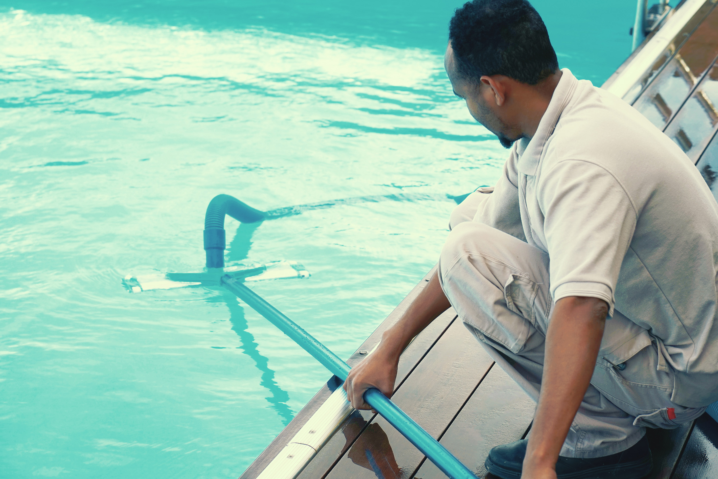 swimming pool technician giving maintenance to a swimming pool